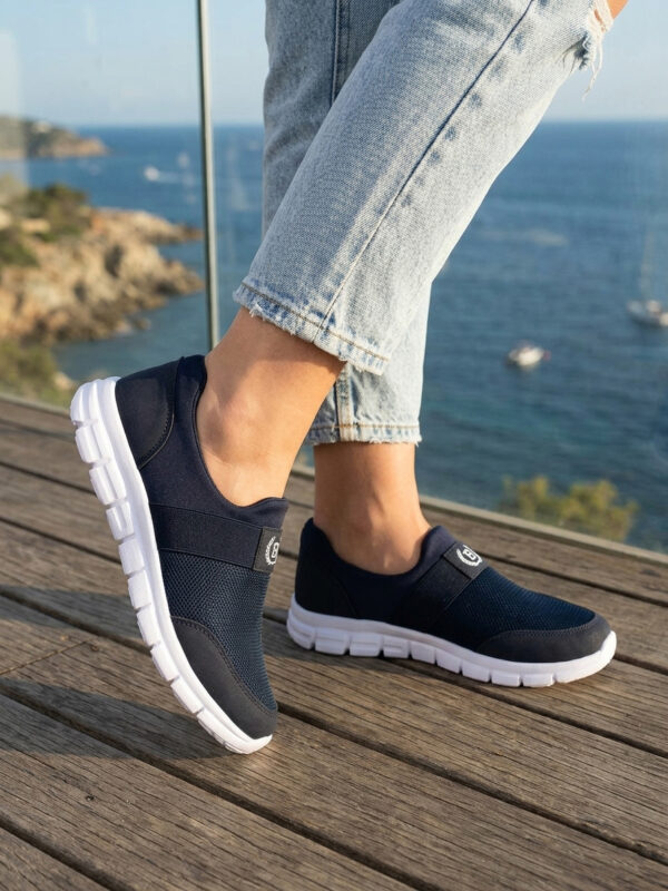 Sokakta yürüyen bir modelin ayağında siyah renkli, bağcıksız, hafif tekstil malzemeden üretilmiş erkek slip-on sneaker ayakkabı.