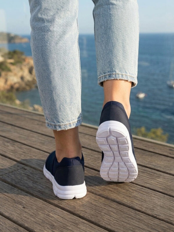 Sokakta yürüyen bir modelin ayağında siyah renkli, bağcıksız, hafif tekstil malzemeden üretilmiş erkek slip-on sneaker ayakkabı.