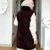 Kahverengi kürk yakalı fermuarlı uzun yelek, krem pantolon ve kazakla kombin