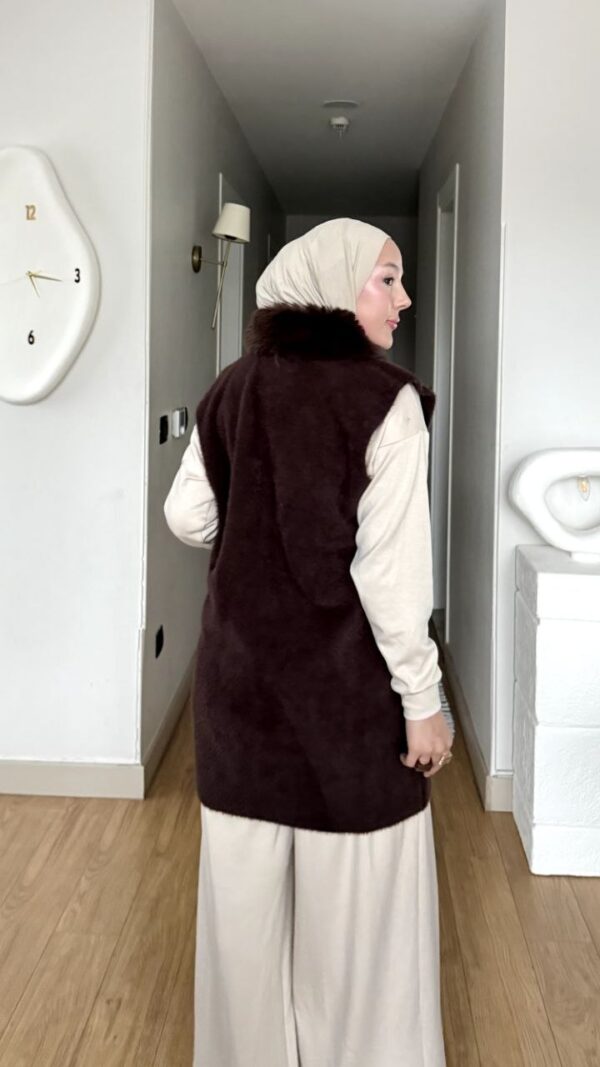 Kahverengi kürk yakalı fermuarlı uzun yelek, krem pantolon ve kazakla kombin