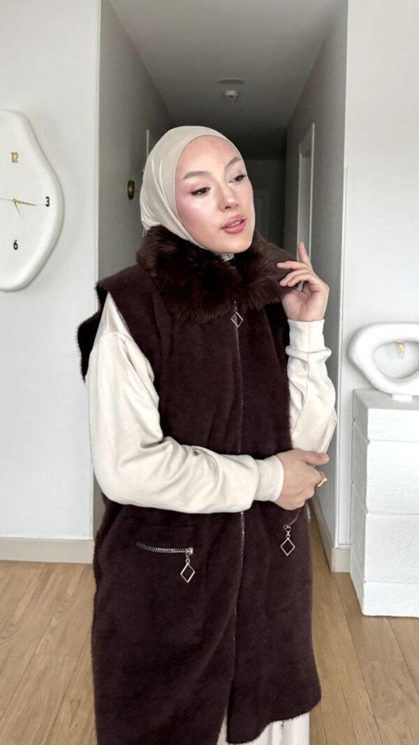 Kahverengi kürk yakalı fermuarlı uzun yelek, krem pantolon ve kazakla kombin